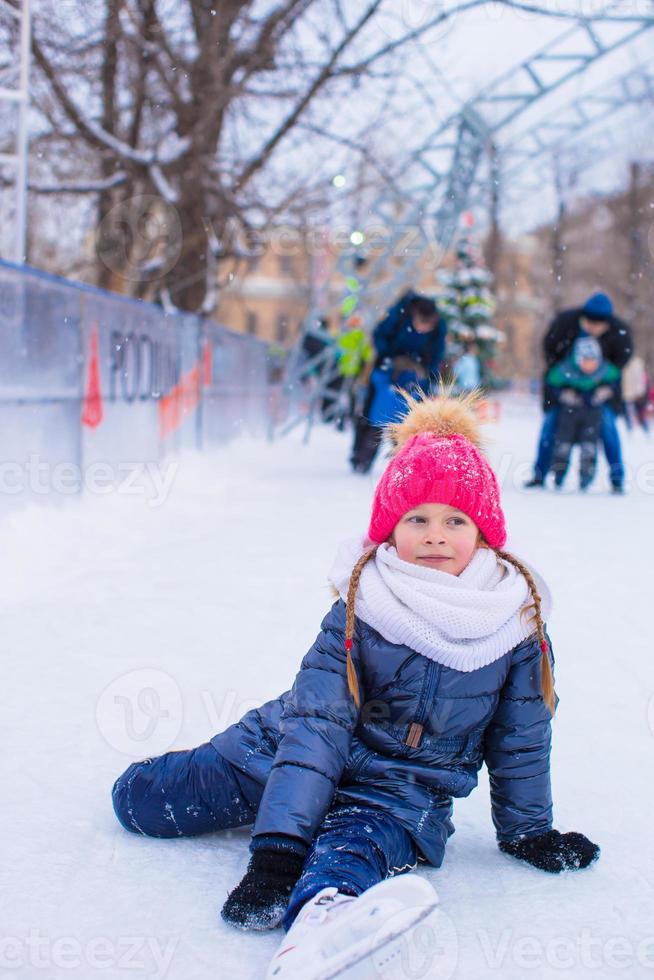 weinig aanbiddelijk meisje zittend Aan ijs met skates na vallen foto