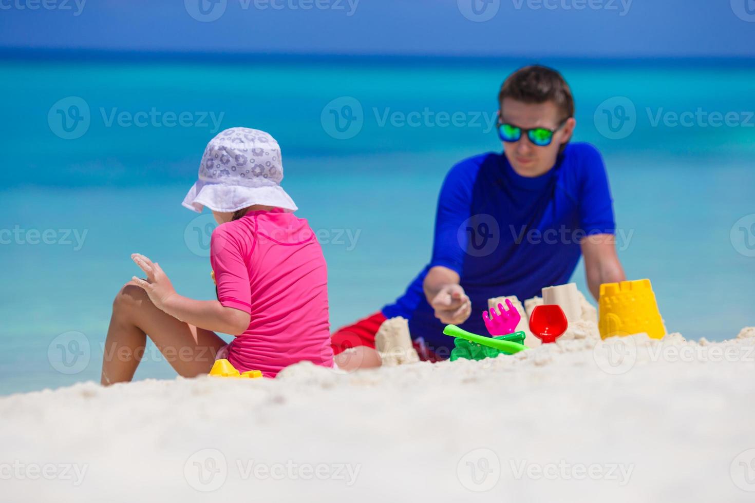 aanbiddelijk weinig meisje en gelukkig vader spelen met strand speelgoed Aan zomer vakantie foto