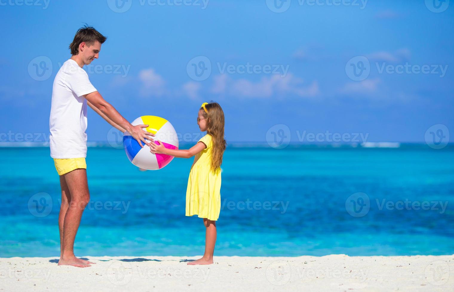 gelukkig vader en dochter spelen met bal hebben pret buitenshuis Aan strand foto