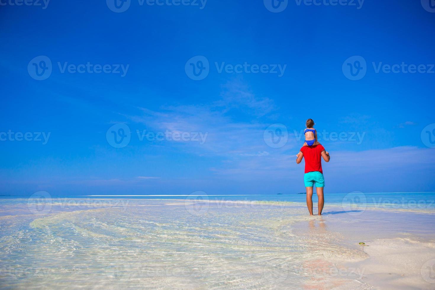 gelukkige vader en zijn schattige dochtertje op tropisch strand met plezier foto