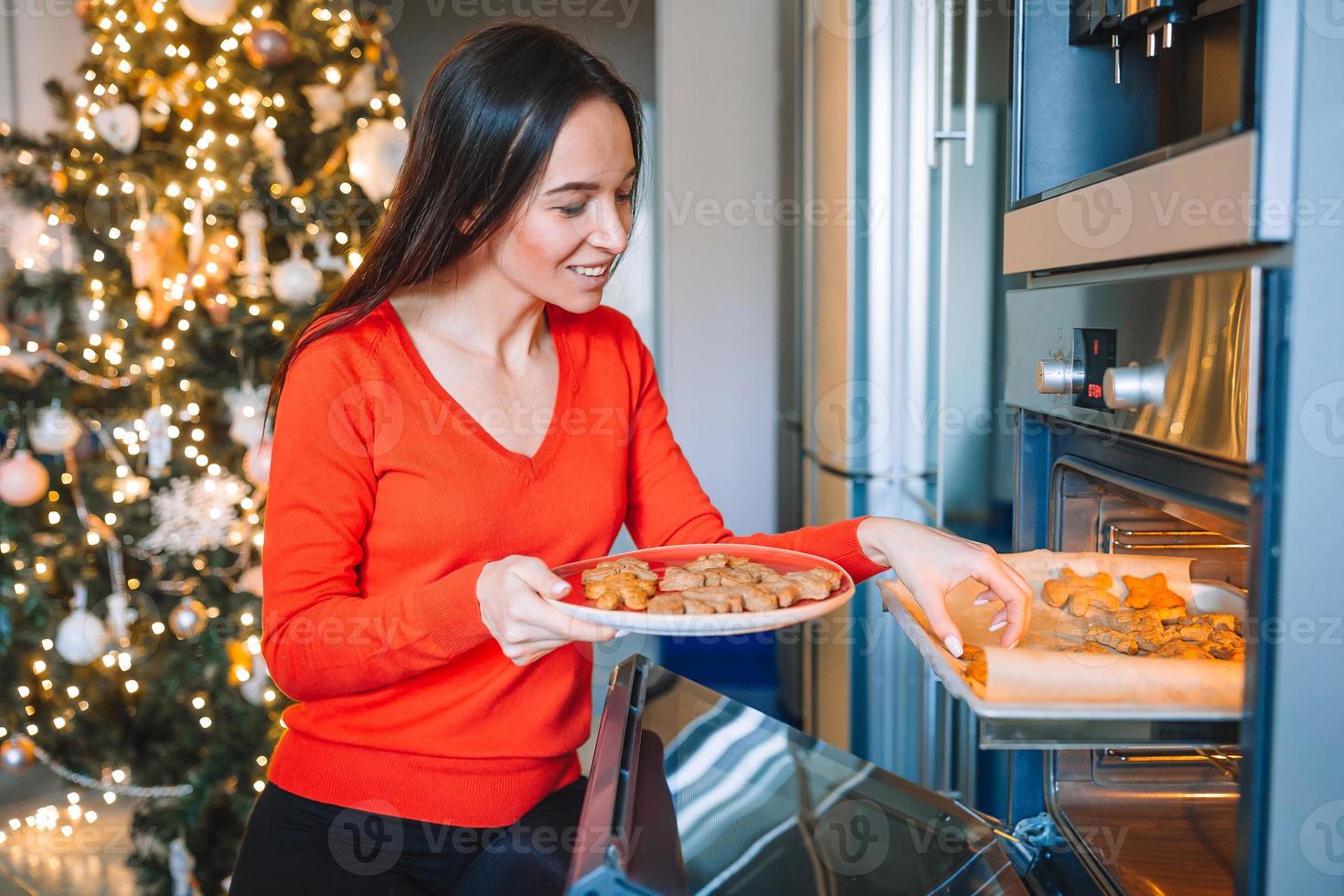 jong vrouw in Kerstmis hoed bakken peperkoek Bij huis. foto