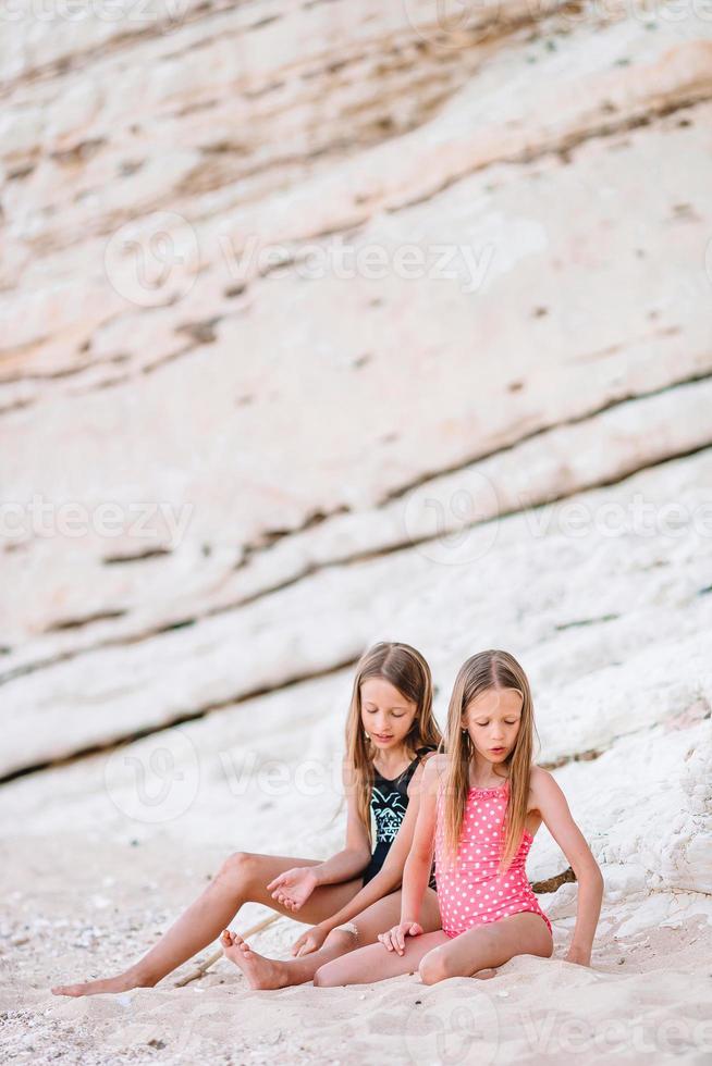 twee weinig gelukkig meisjes hebben een veel van pret Bij tropisch strand spelen samen foto