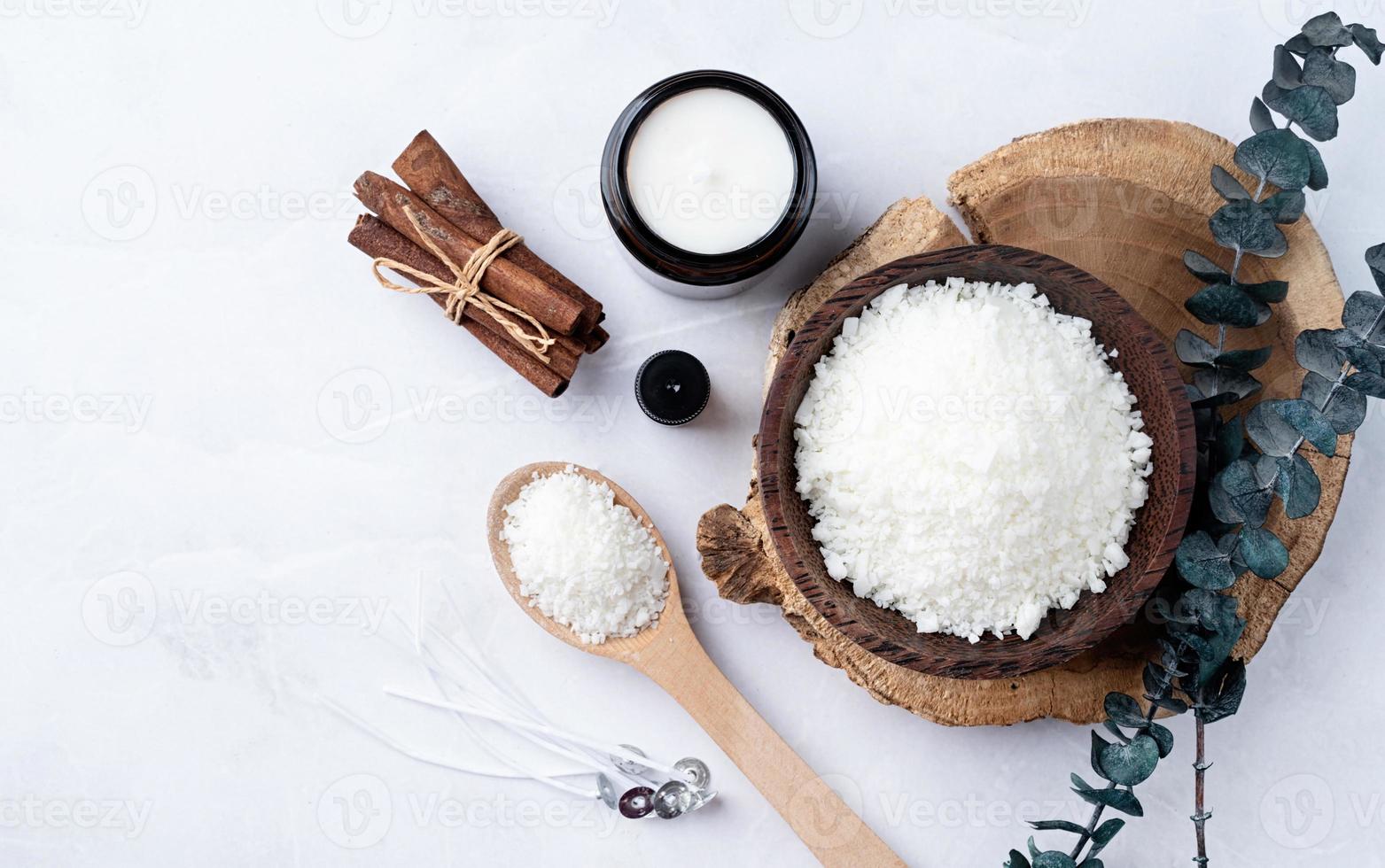 ingrediënten voor kaars maken , soja was- vlokken, kaarsen, kaneel wieken en houten lepels Aan licht marmeren achtergrond foto