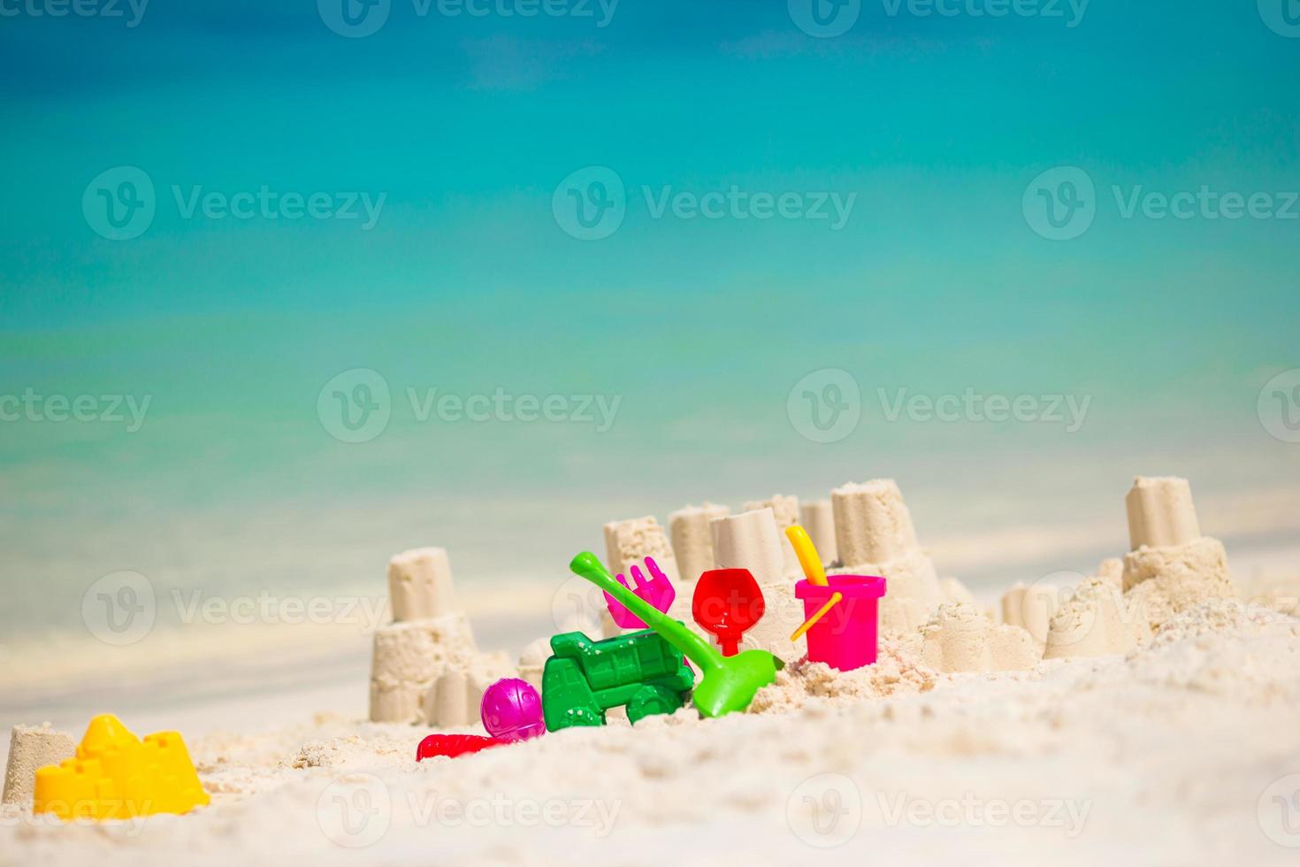 Zandkasteel Bij wit strand met plastic kinderen speelgoed foto