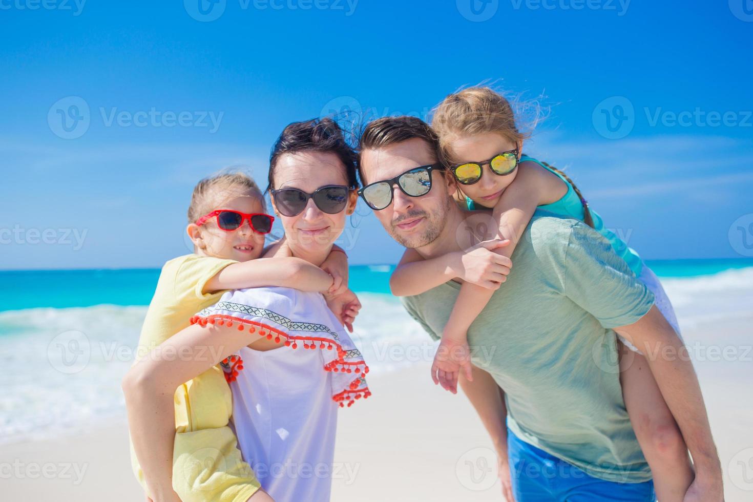 gelukkig mooi familie van vier Aan een tropisch strand foto