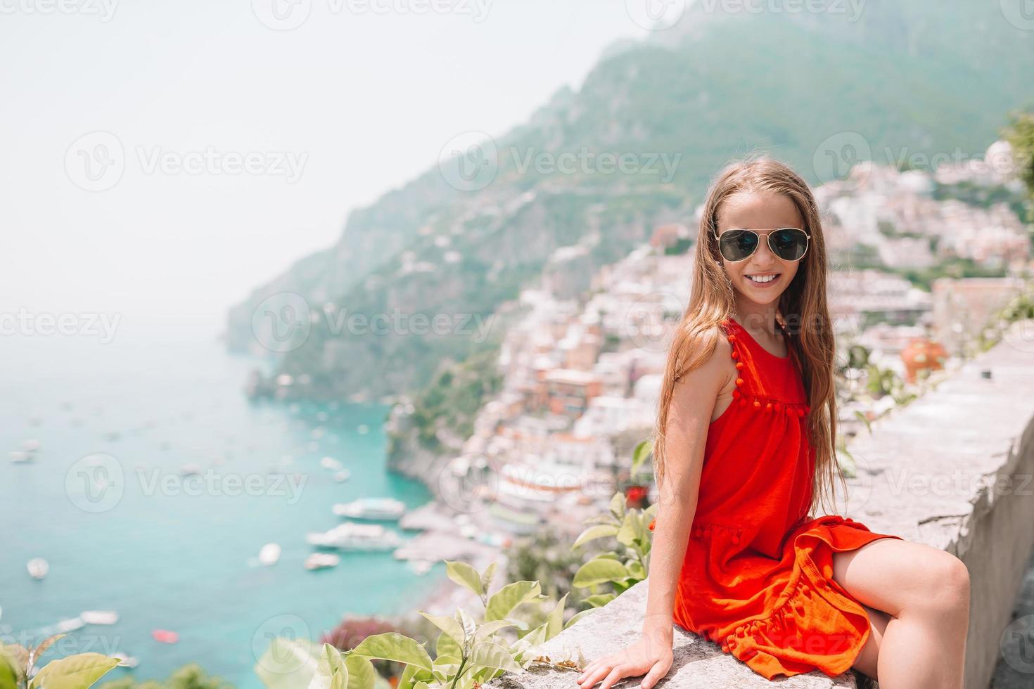 aanbiddelijk weinig meisje Aan warm en zonnig zomer dag in positano stad- in Italië foto