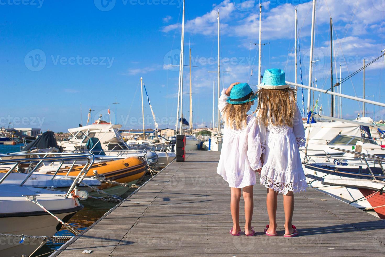 aanbiddelijk weinig meisjes wandelen in een haven Aan zomer dag foto