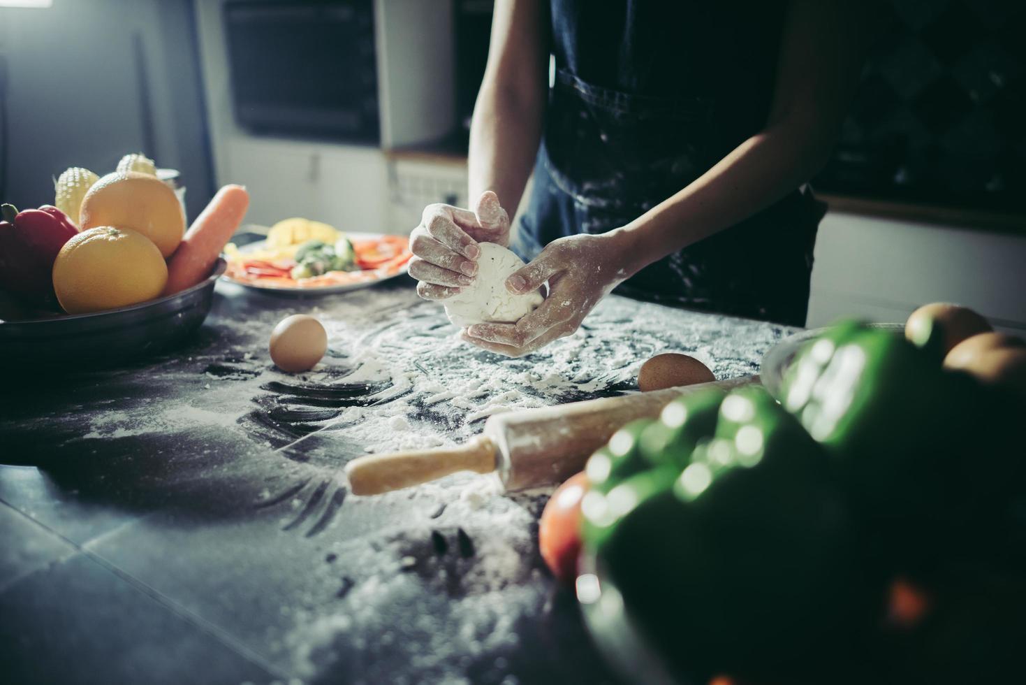 vrouw kneedt deeg voor pizza foto