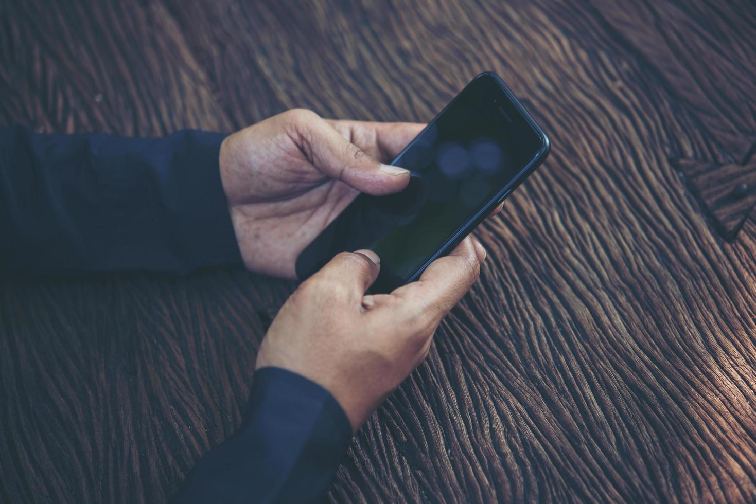 persoon met slimme telefoon aan een tafel foto