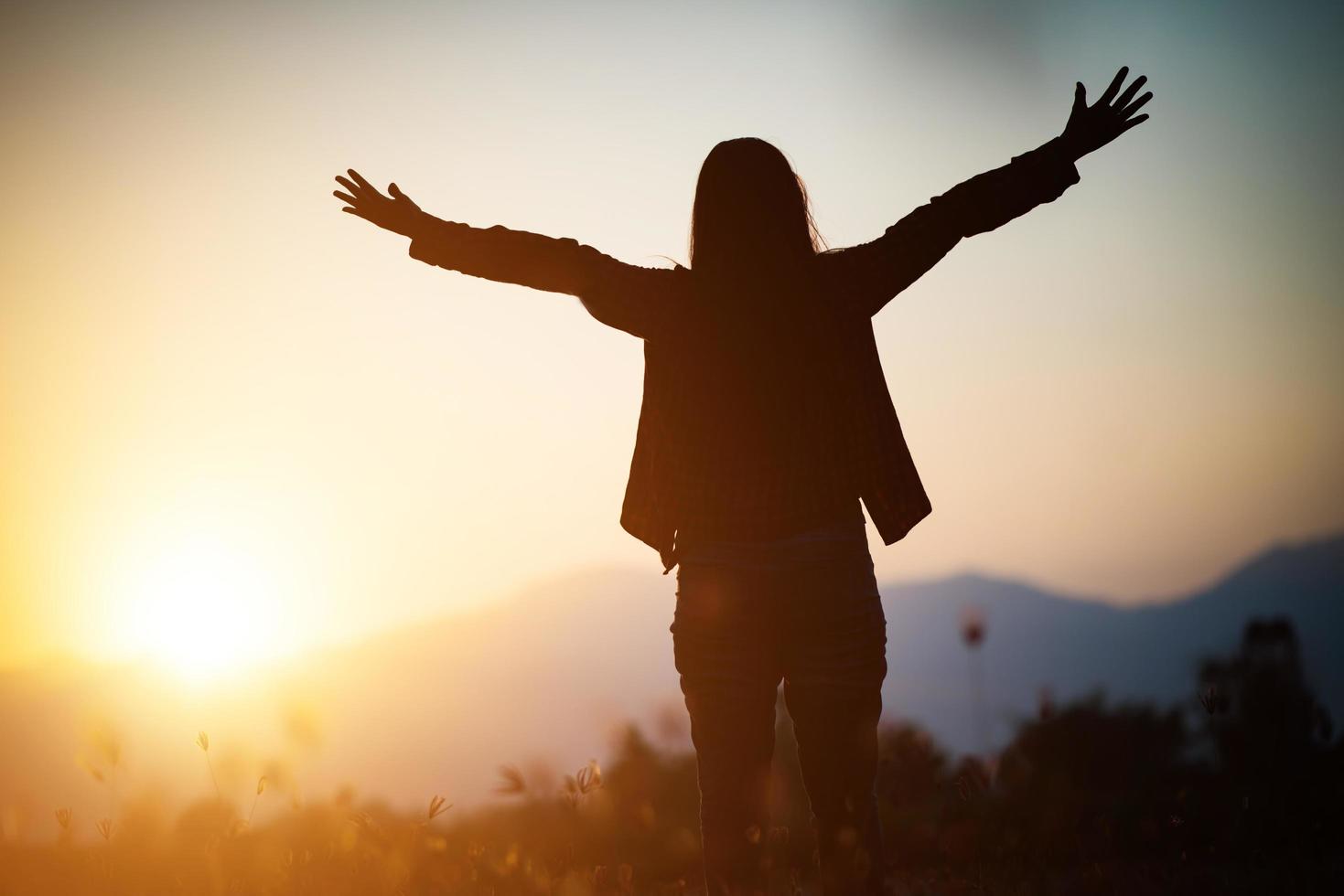 silhouet van een vrouw die bidt over mooie hemelachtergrond foto