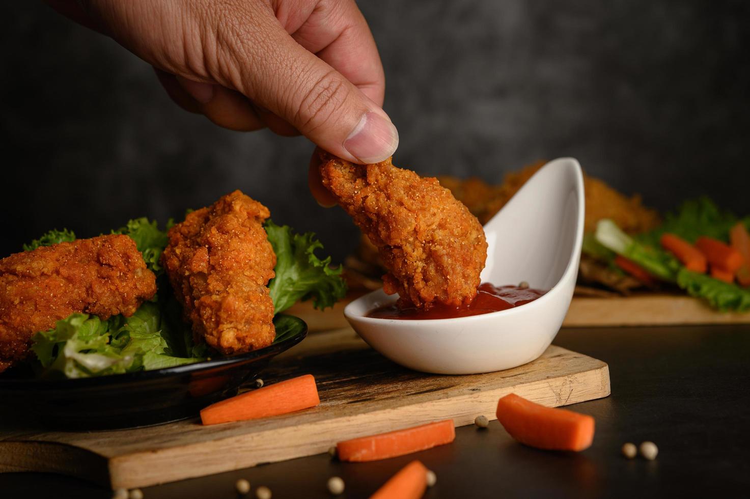 hand krokant gebakken kip in saus dompelen foto