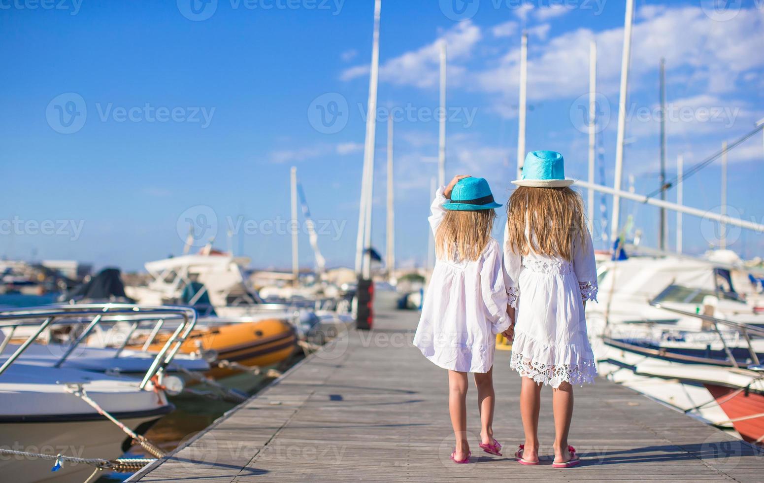 aanbiddelijk weinig meisjes wandelen in een haven Aan zomer dag foto
