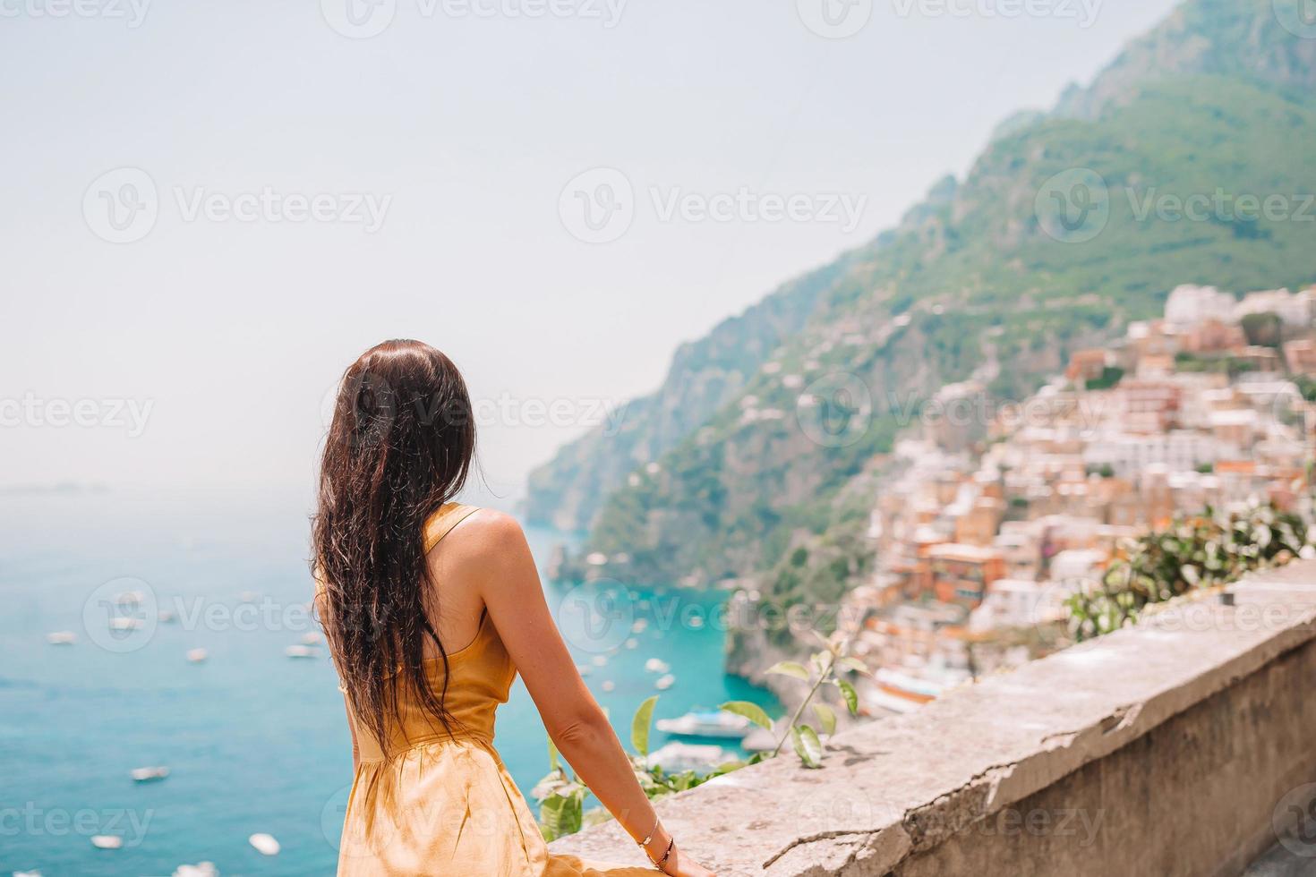 zomer vakantie in Italië. jong vrouw in positano dorp Aan de achtergrond, amalfi kust, Italië foto