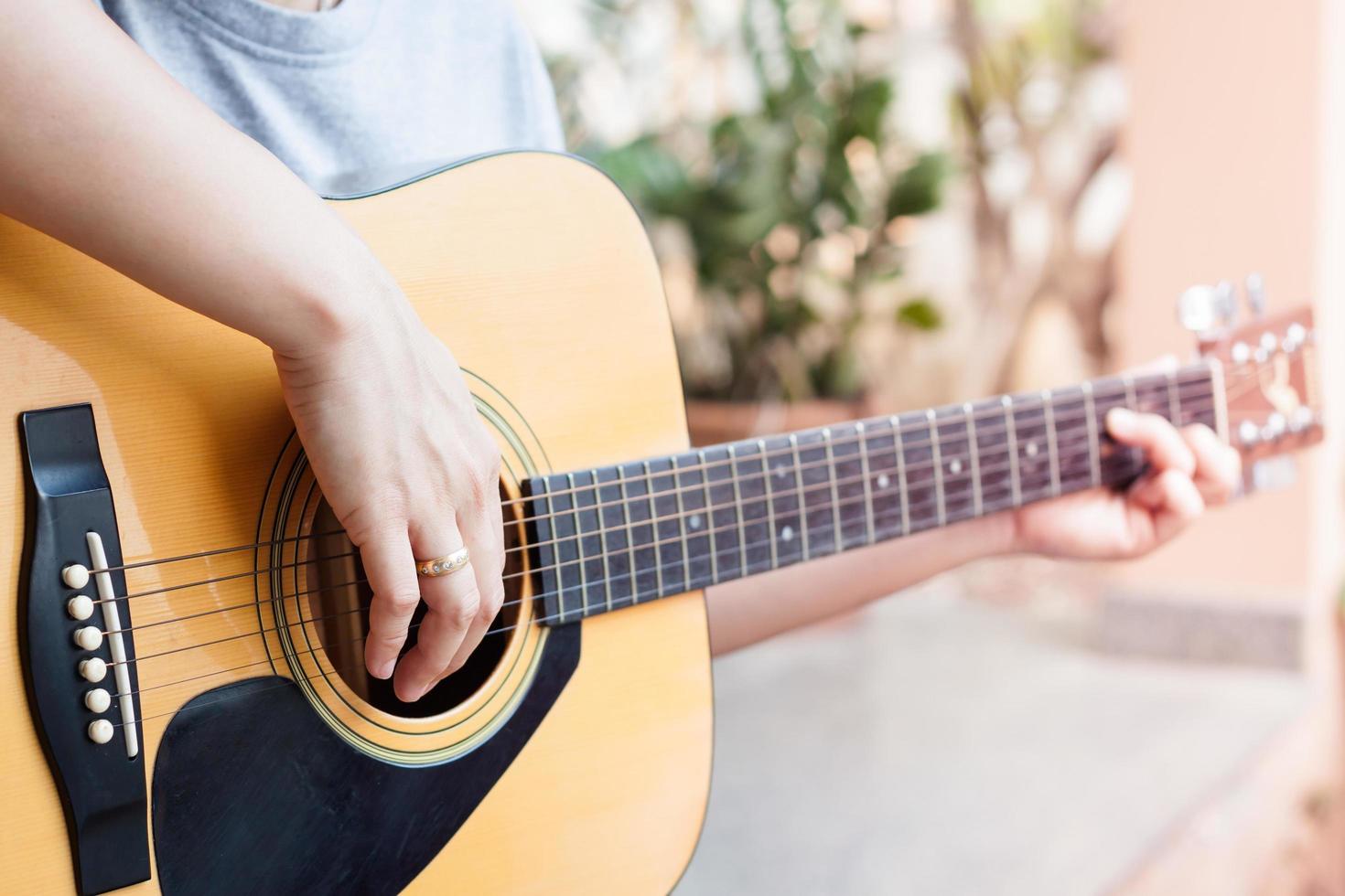 close-up van een persoon die buiten een akoestische gitaar speelt foto