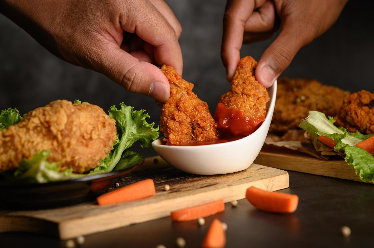 twee handen met krokante kip-offertes in tomatensaus foto