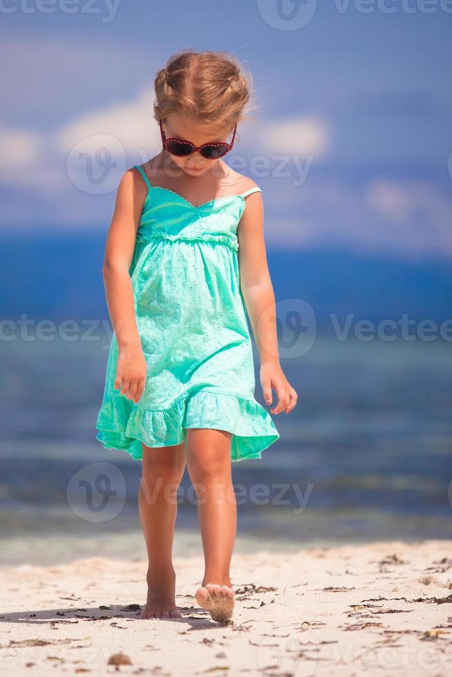 schattig klein meisje lopen op tropisch wit strand foto