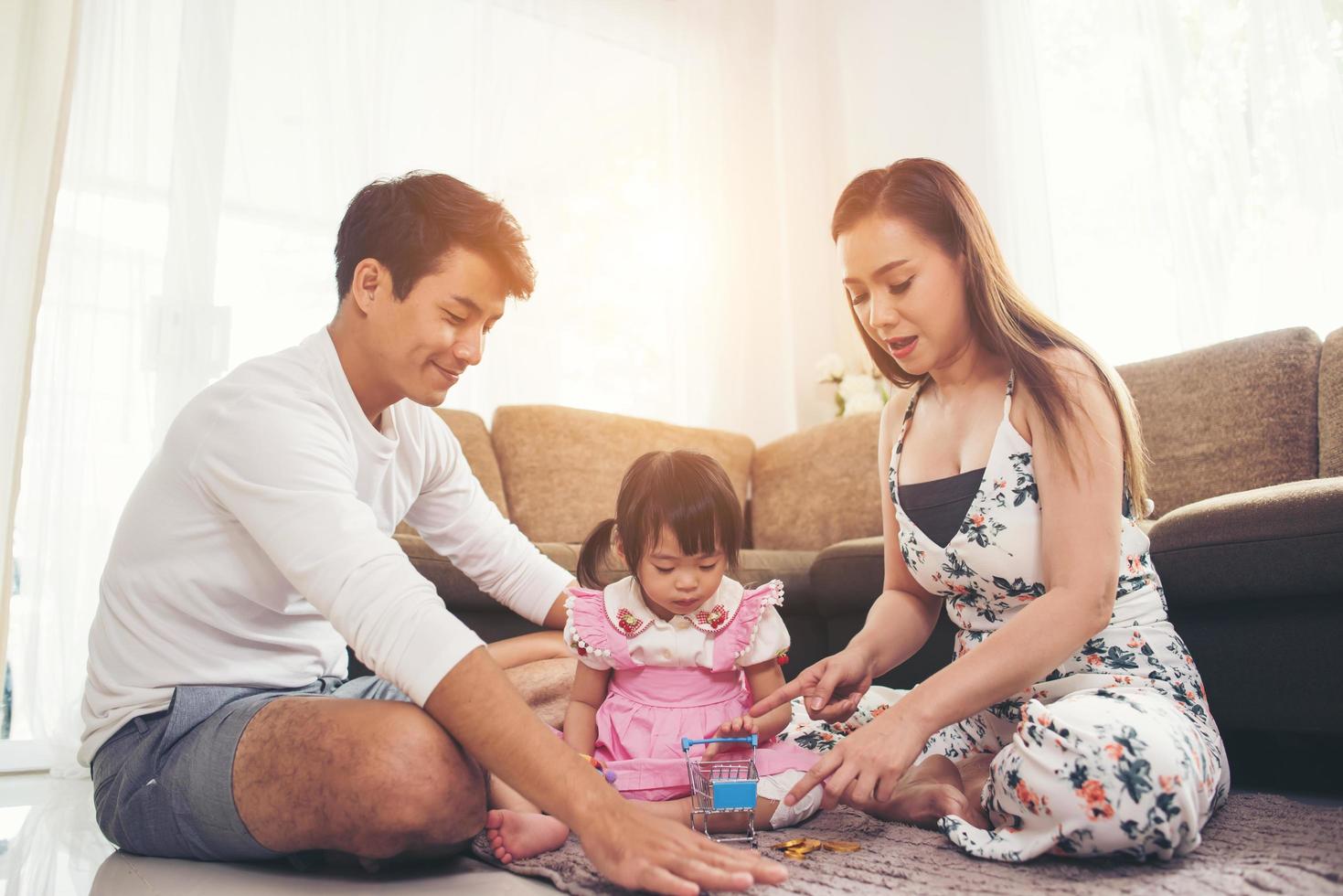 kind met haar ouders die thuis op de vloer spelen foto