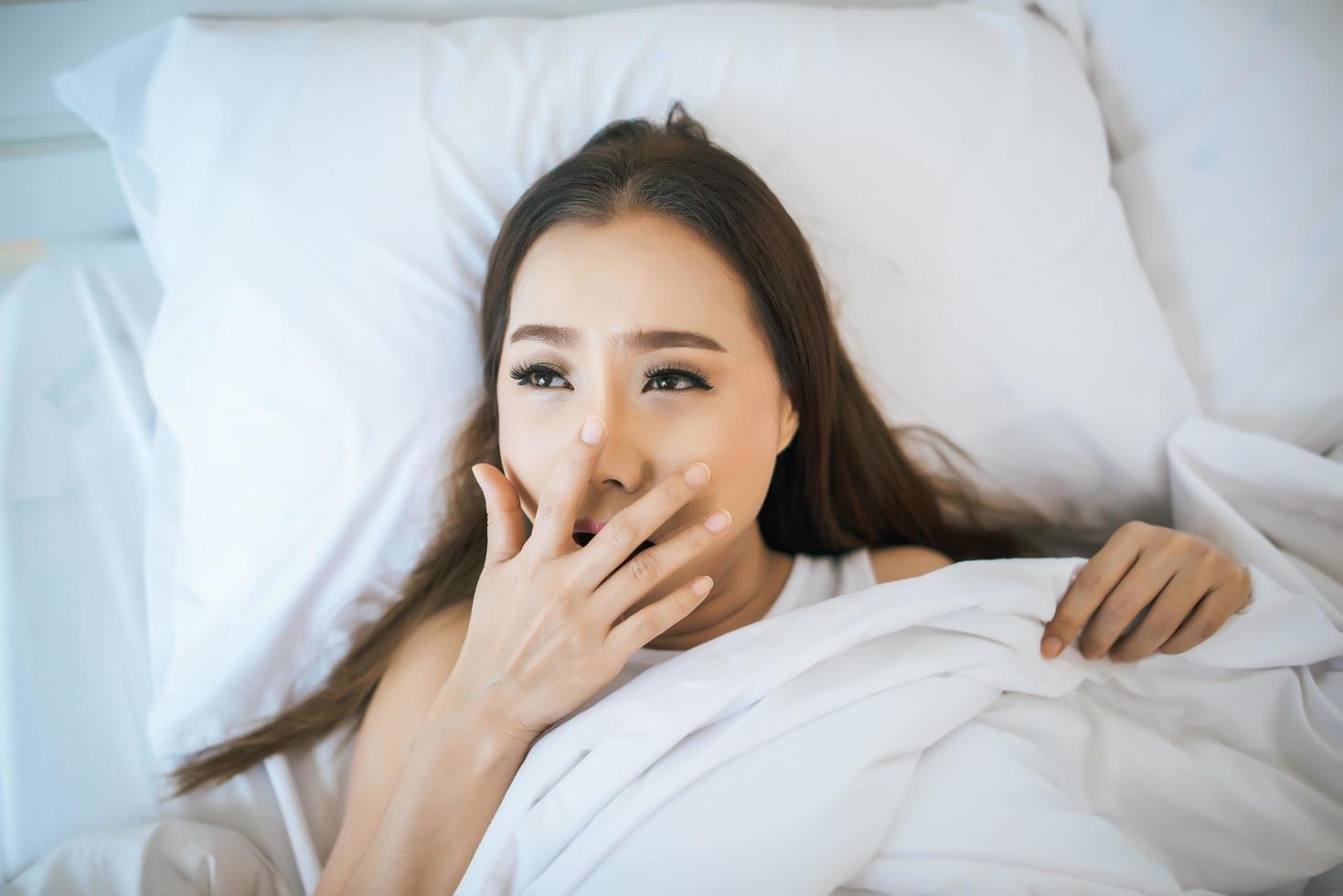 vrouw wordt wakker in haar bed, lui in de ochtend foto