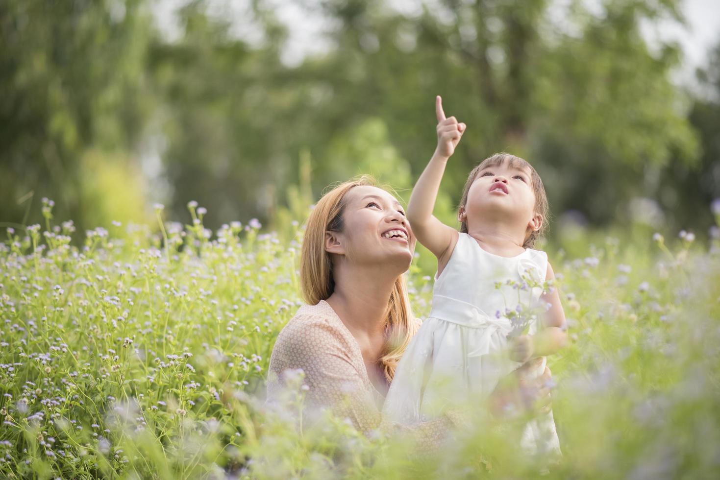 moeder en dochtertje spelen samen in een veld wilde bloemen foto