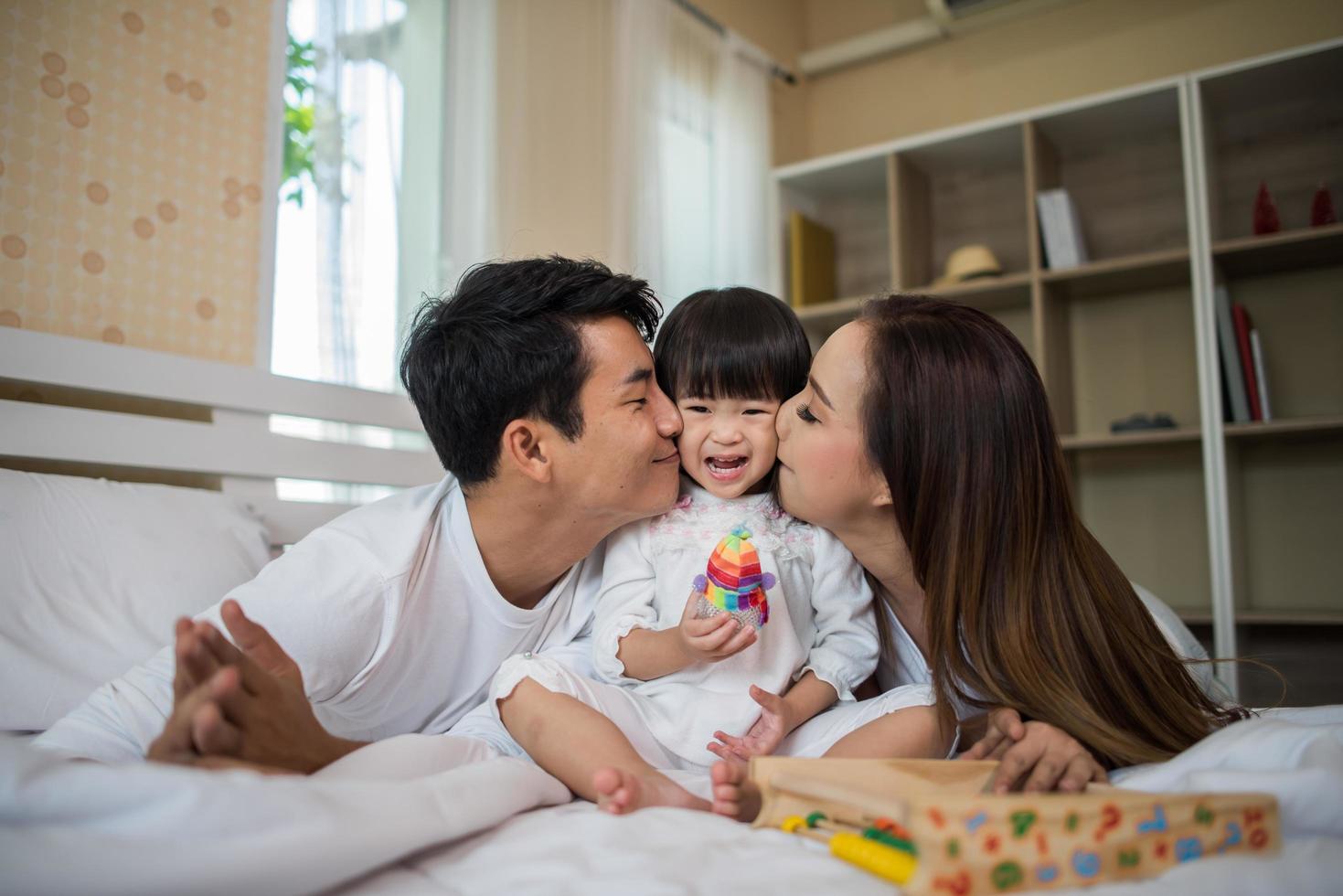 gelukkig kind met ouders die thuis spelen foto