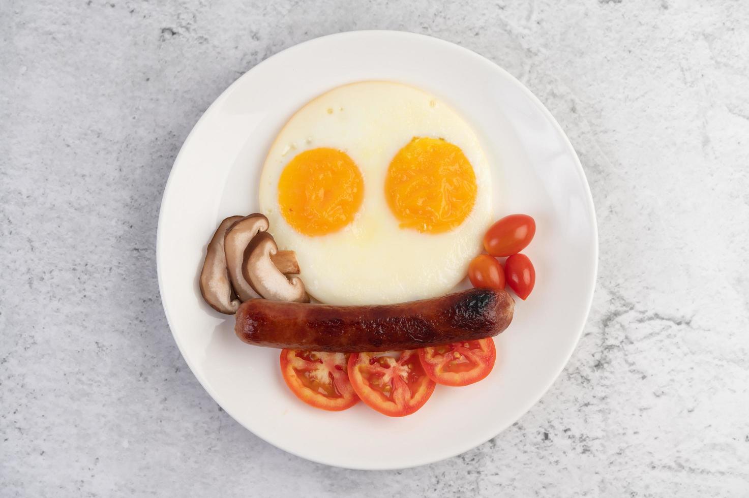 ontbijtbord met gebakken eieren, tomaten, chinese worst en champignons foto