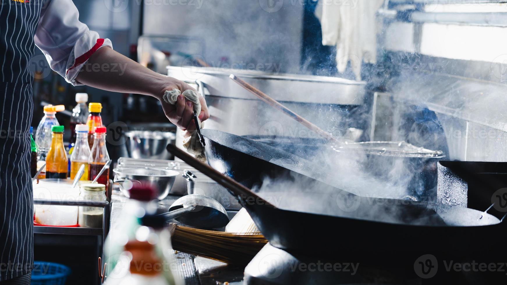 chef-kok die roerbak in een wok maakt foto