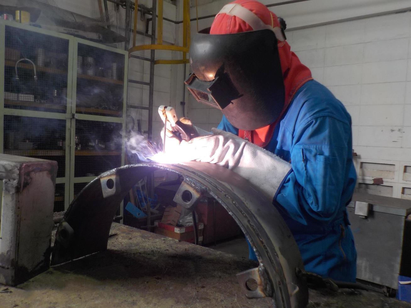 lasser in blauw uniform lassen van het werkstuk foto