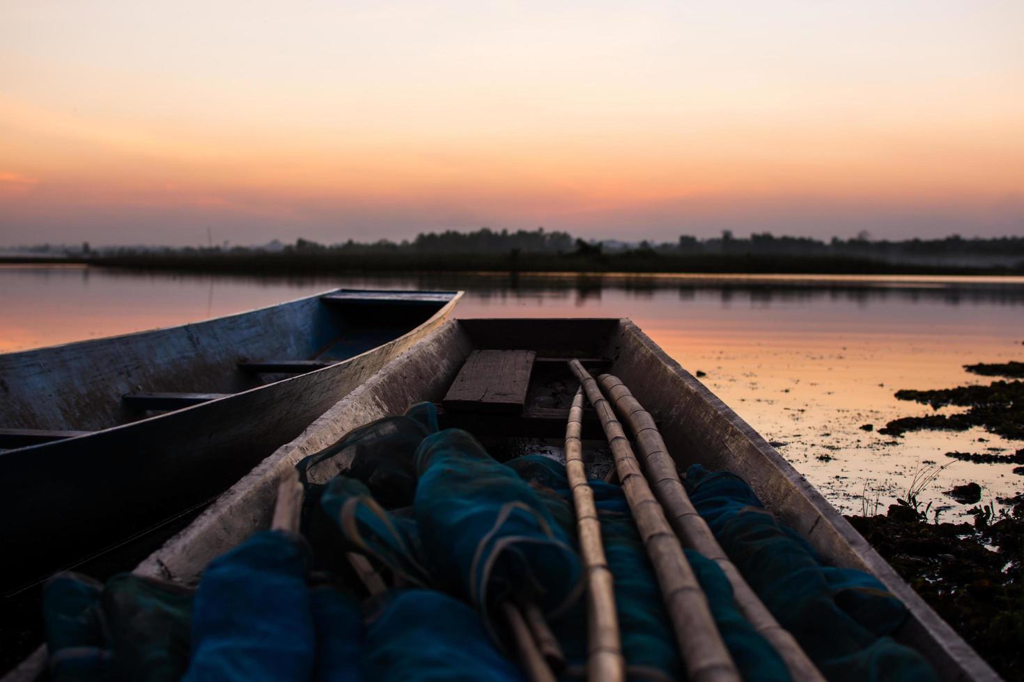houten boot afgemeerd aan een rivier bij zonsondergang foto