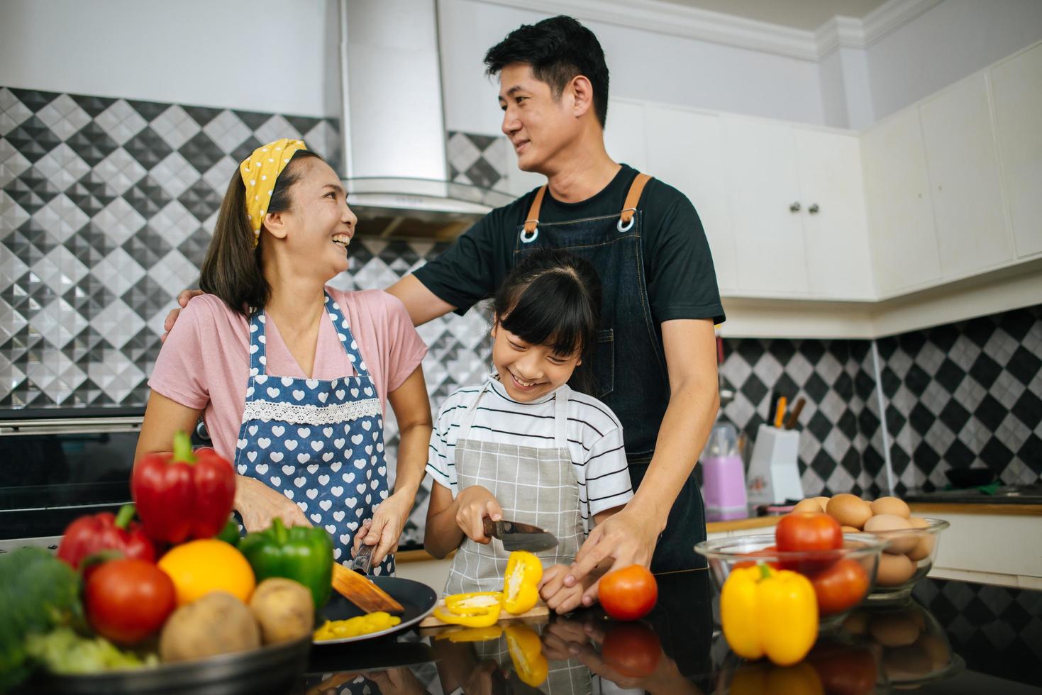 gelukkige familie samen groenten snijden in hun keuken foto