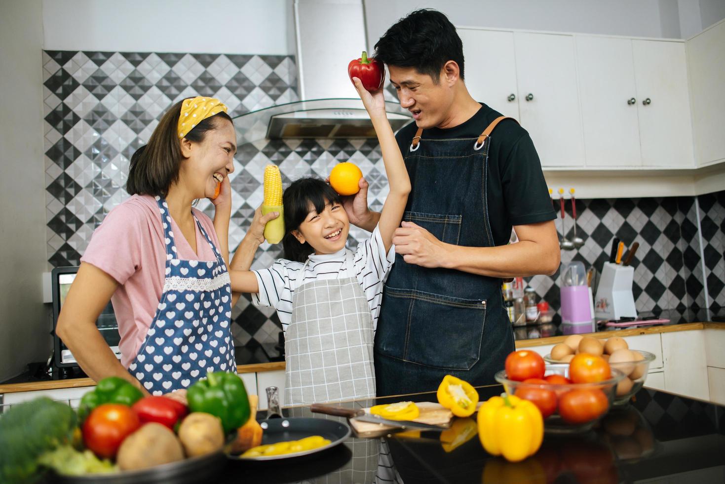 gelukkige familie samen groenten snijden in hun keuken foto