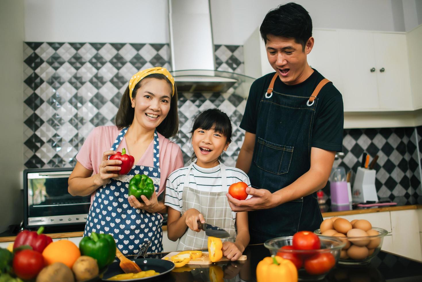 gelukkige familie samen groenten snijden in hun keuken foto
