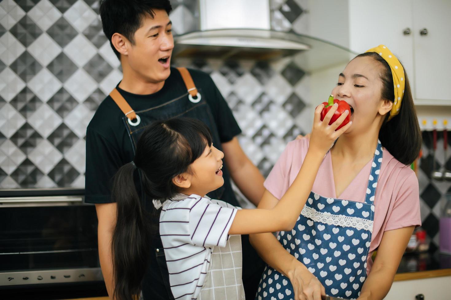 gelukkige familie samen groenten snijden in hun keuken foto