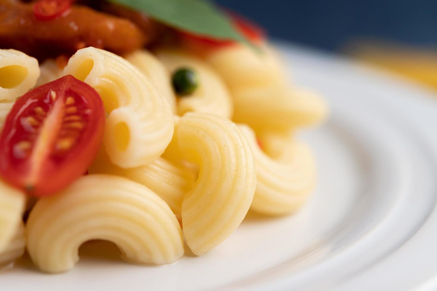 roergebakken macaroni met tomaat, chili, peperzaadjes en basilicum foto