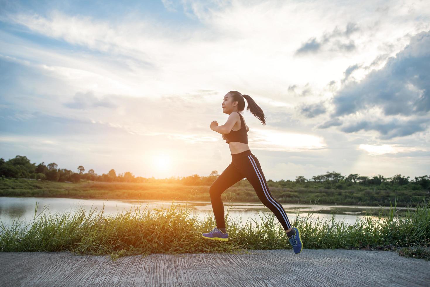 een jonge gelukkige vrouwelijke atleet die buitenshuis jogt foto