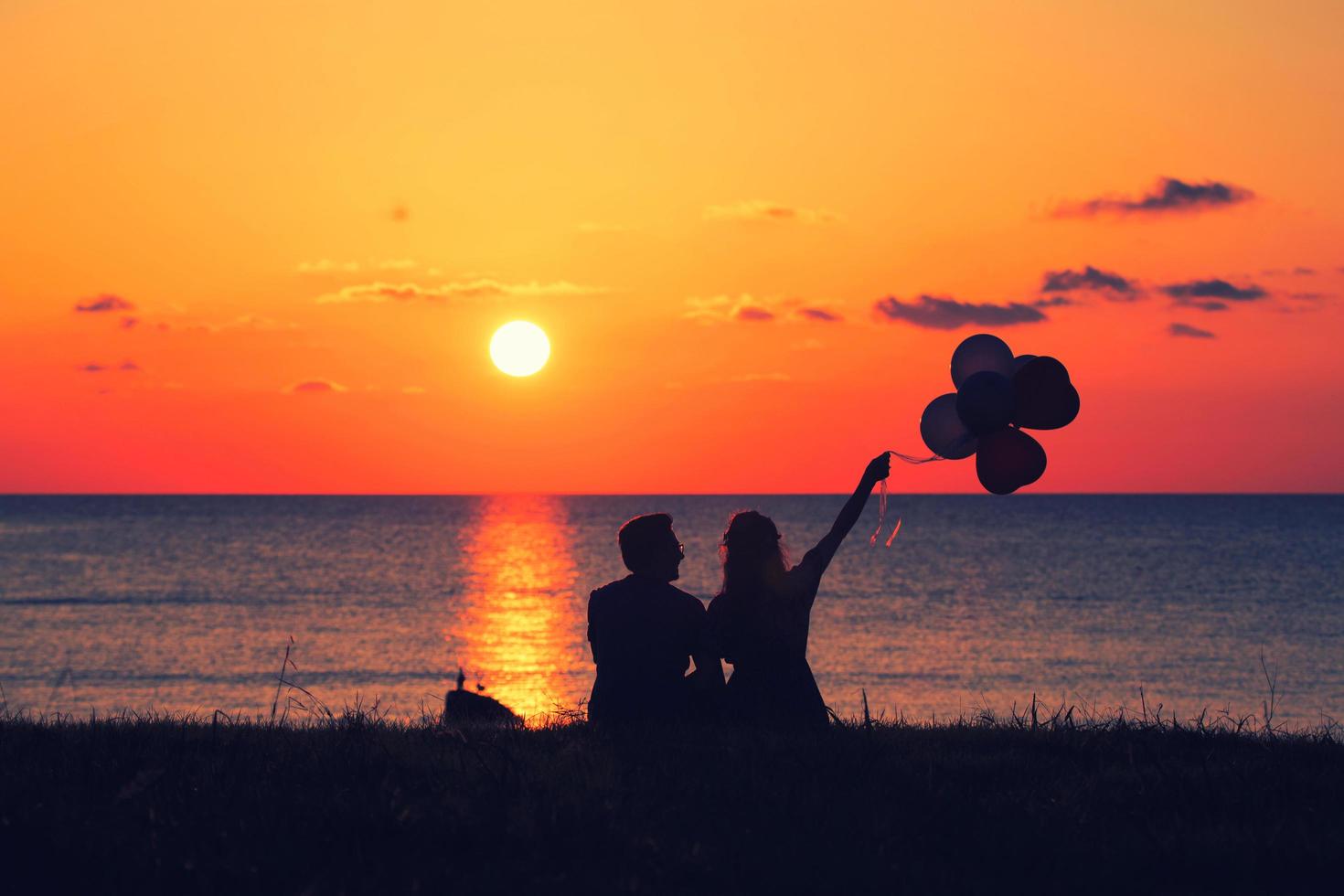 twee mensen met ballonnen op de zonsondergang foto