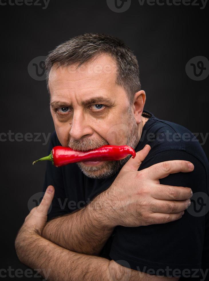 ouderen Mens met rood peper in zijn mond foto