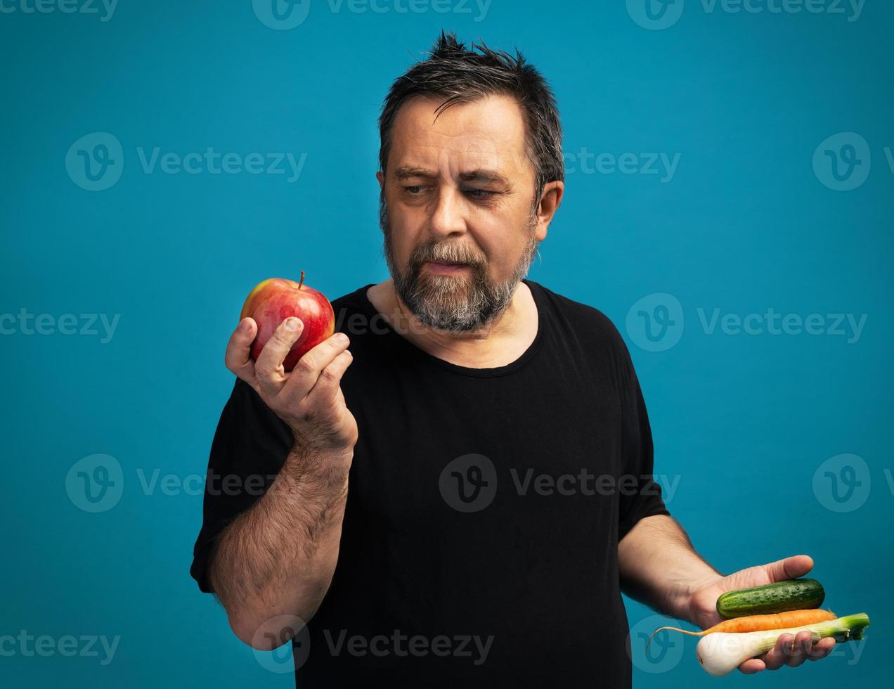 Mens in een zwart t-shirt houdt fruit en groenten foto