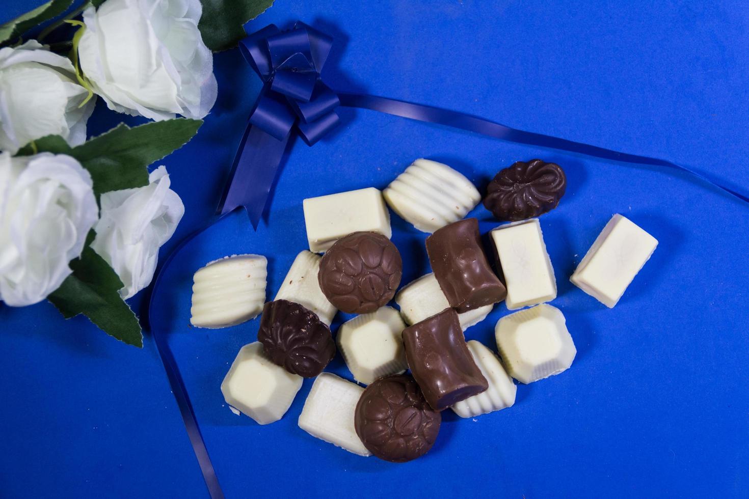 verscheidenheid van zoet chocola bonbons en wit rozen foto