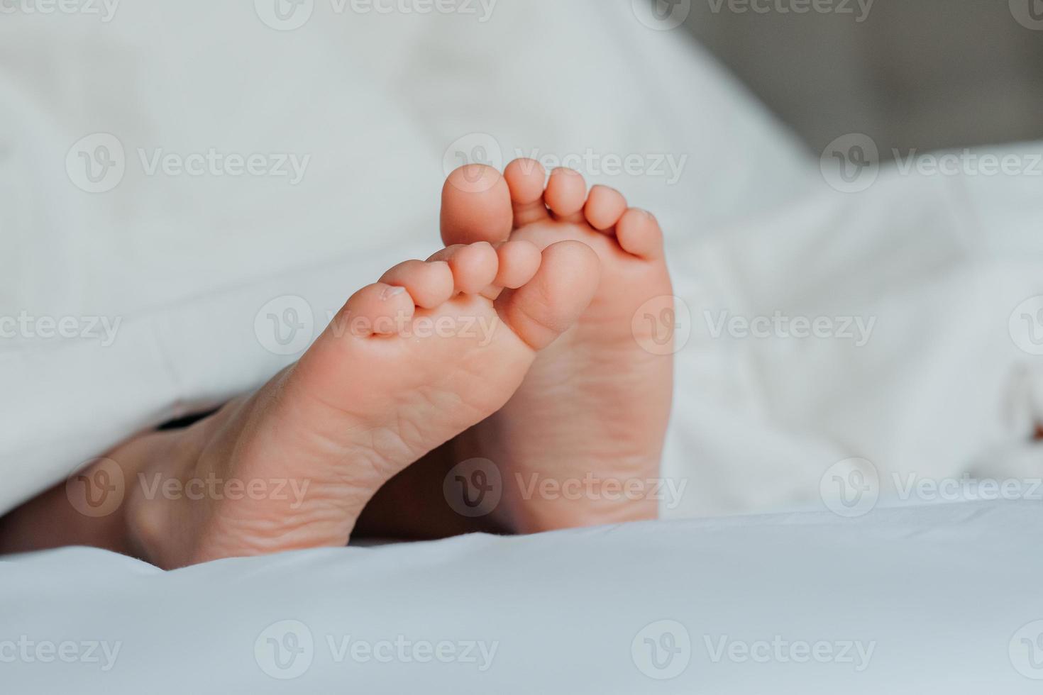 visie Aan kind kaal voeten Aan wit bed. slaapkamer lit met ochtend- licht. kind slaapt in pyjama comfort foto