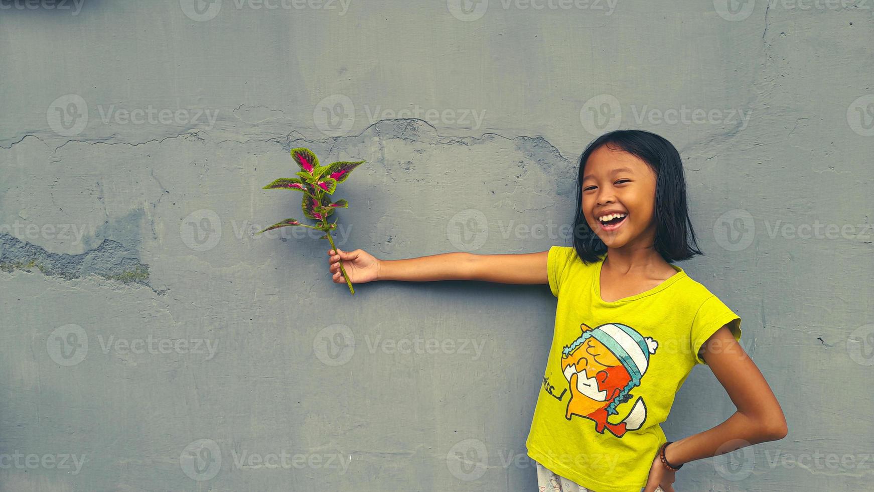 weinig meisje Holding jong fabriek. groen bladeren. ecologie concept. licht kleur achtergrond. foto