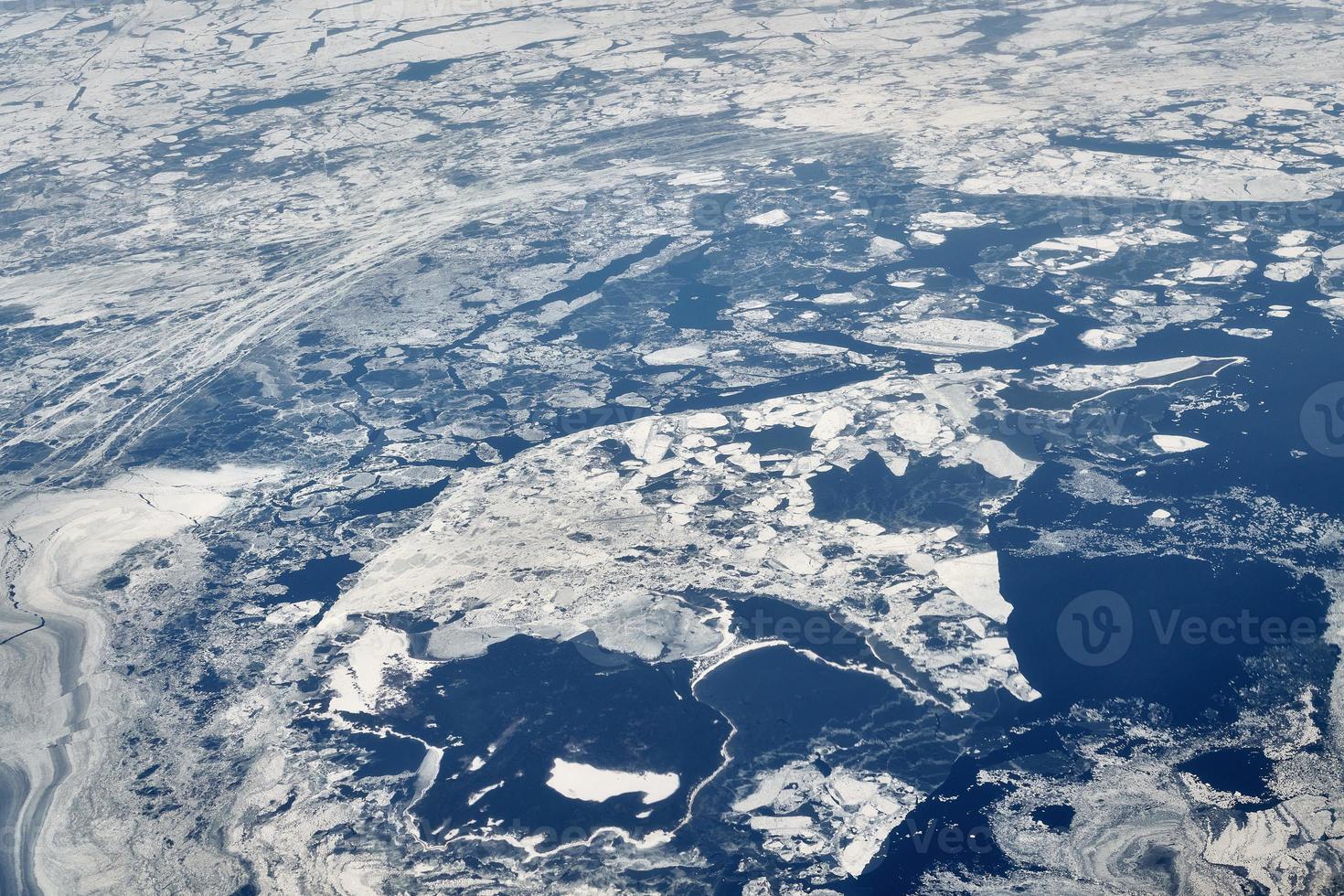 antenne visie van vliegtuig venster over- wolken top naar sneeuw gedekt bevroren zee, winter vers ijzig lucht foto