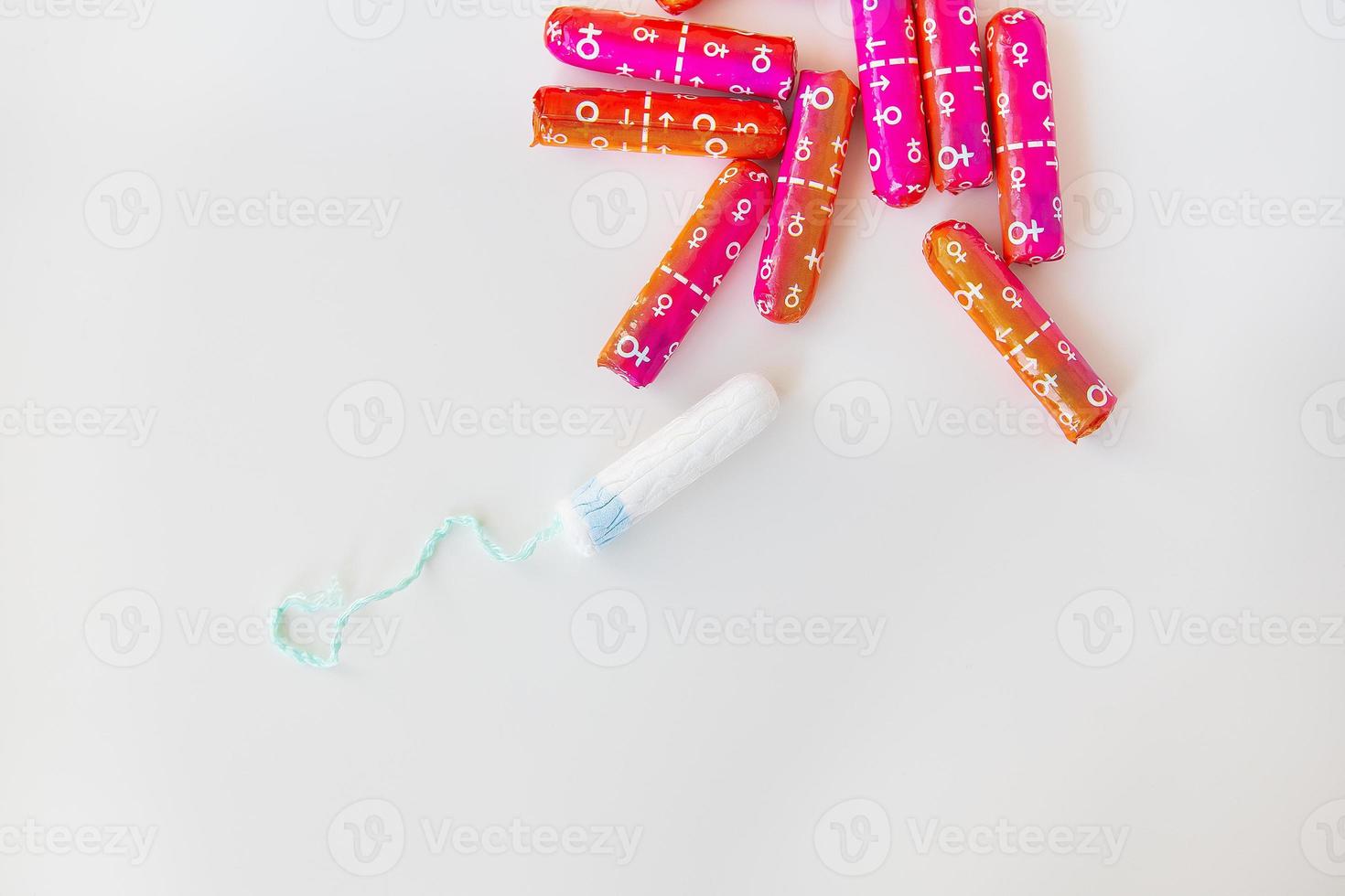 medisch vrouw tampon in roze en oranje verpakking Aan een wit achtergrond. hygiënisch wit tampon voor Dames. katoen wattenstaafje. menstruatie, anticonceptie. foto