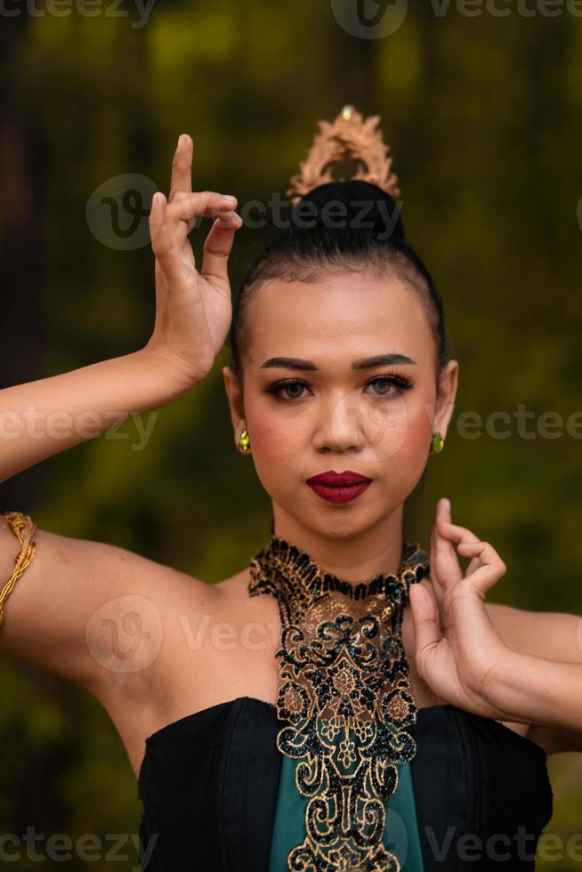 dapper gezicht van een Aziatisch vrouw in een traditioneel groen kostuum met gouden accessoires Aan haar lichaam gedurende de wedstrijd in een dans festival foto