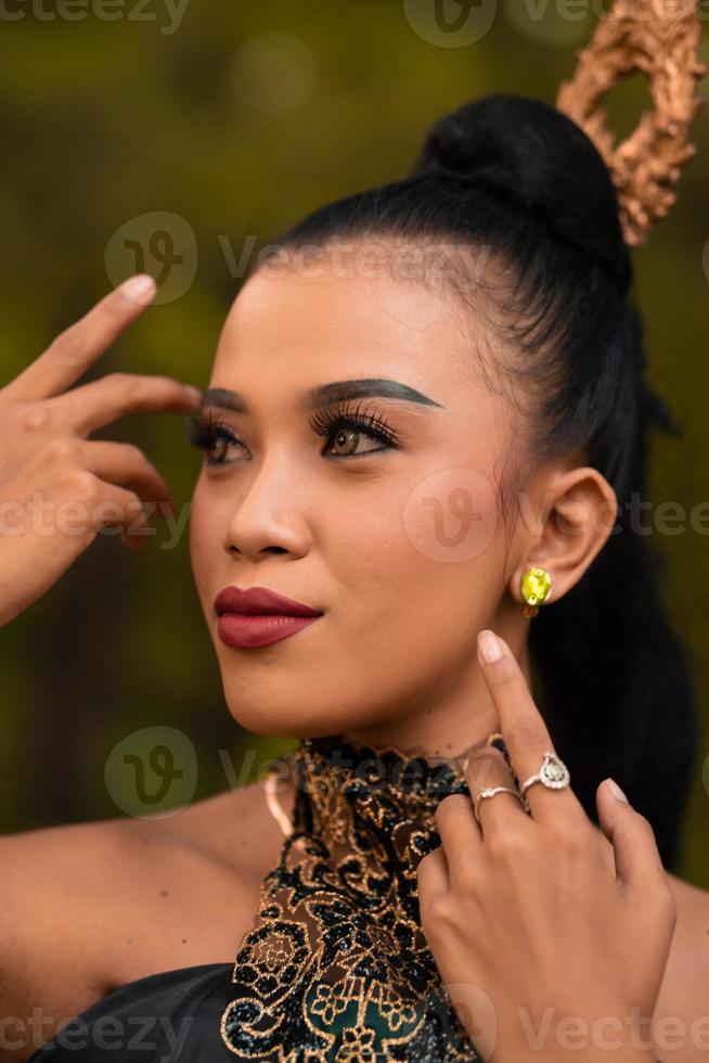 mooi Aziatisch vrouw met bedenken en gebonden zwart haar- vervelend een stuk van zwart sieraden voordat het uitvoeren van dansen Aan de stadium foto