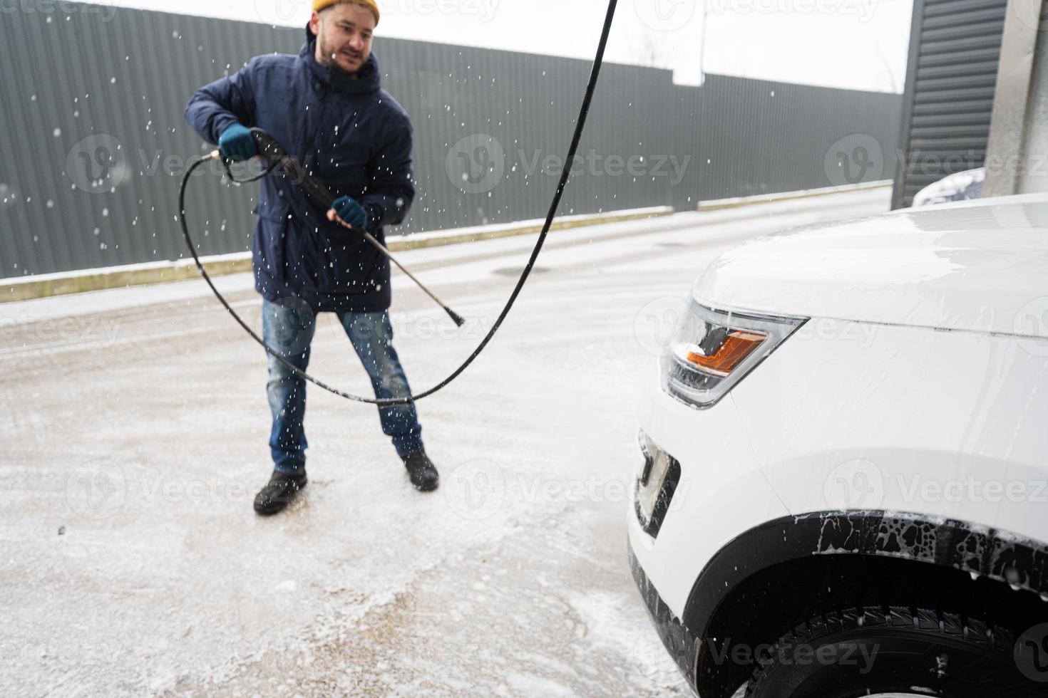 Mens het wassen hoog druk water Amerikaans suv auto Bij zelf onderhoud wassen in verkoudheid het weer. foto