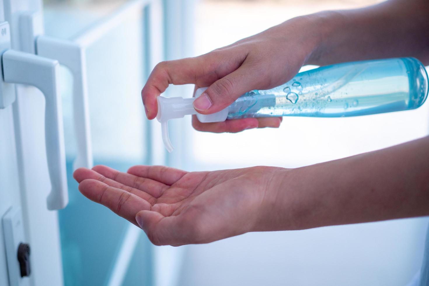 de vrouw toepassingen de gel naar wassen haar handen naar voorkomen besmettelijk ziekten voordat binnengaan en spannend de deur. de concept van voorkomen de verspreiding van ziekte naar familie leden. foto