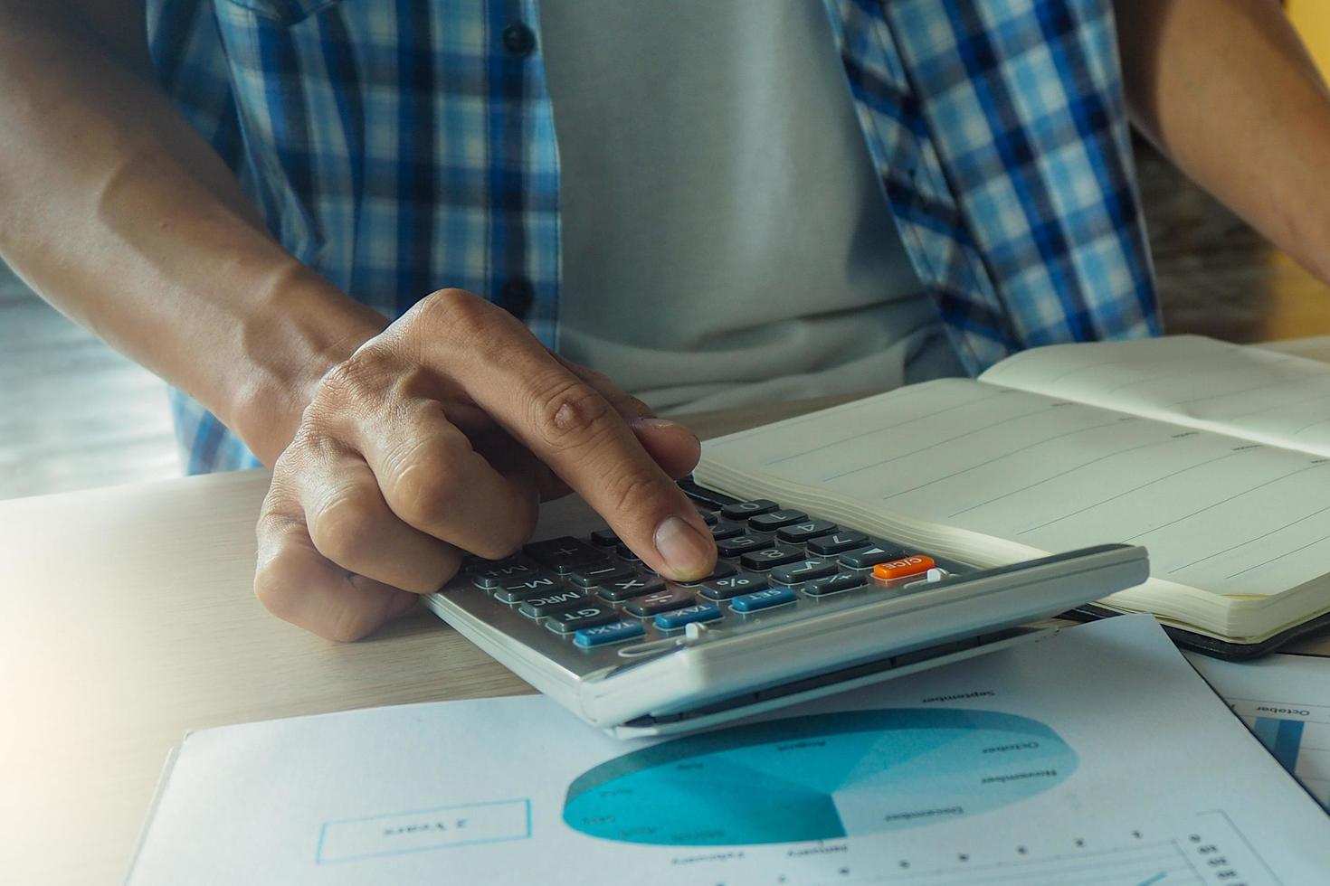 Mens hand- is drukken rekenmachine. berekent de statistisch van omzet in de bedrijf. foto