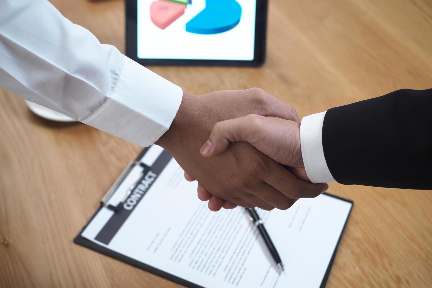 twee zakenlieden toetreden handen naar teken een contract na onderhandelen een investering en winst overeenkomst. foto