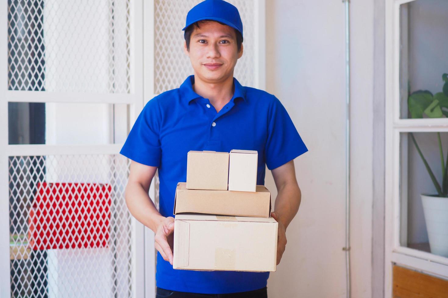 levering personeel met een blauw uniform draag- een bruin pakket doos. levering onderhoud koerier. foto