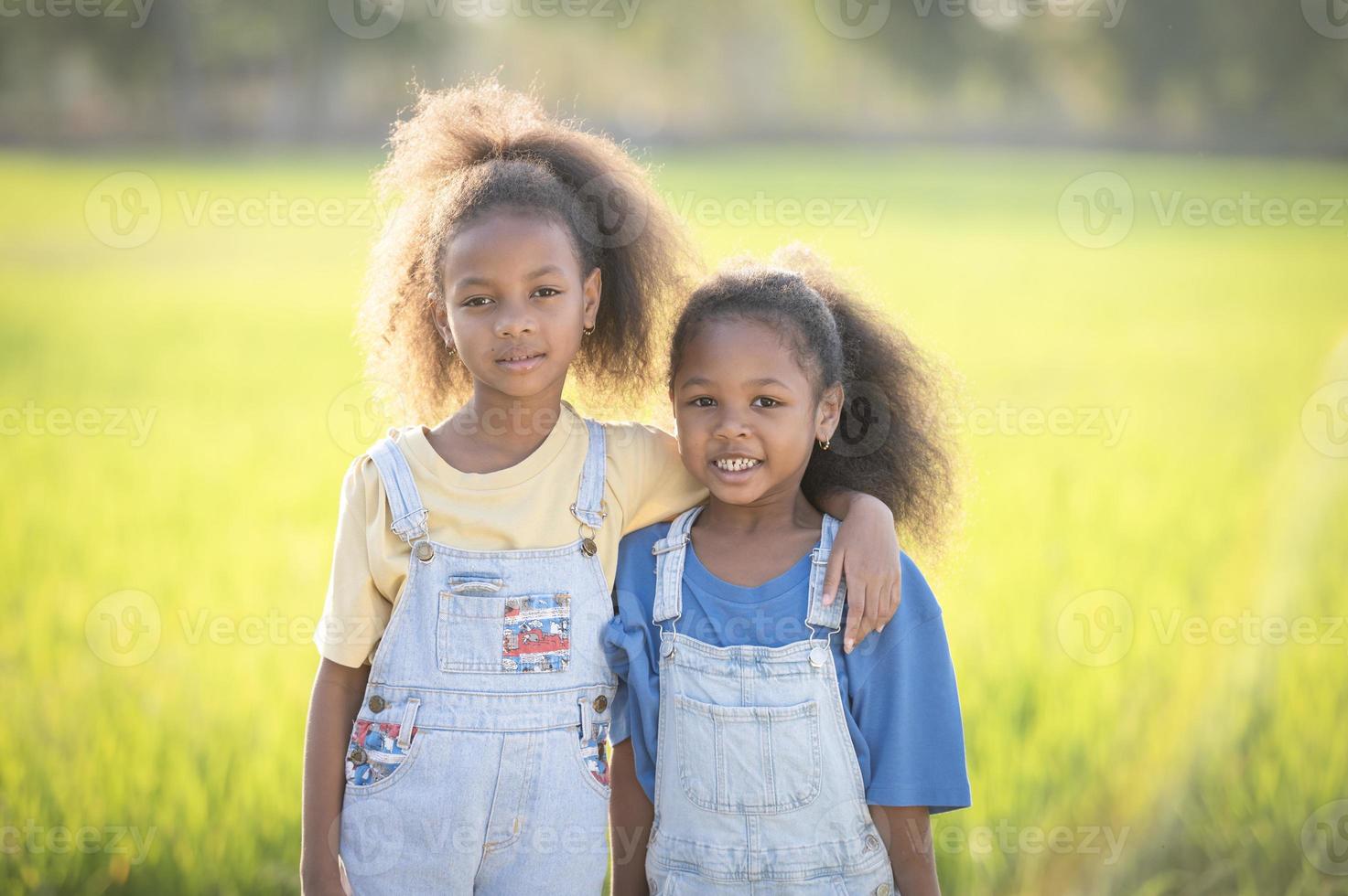 buitenshuis detailopname schot van twee schattig zwart zussen glimlachen Bij zonsondergang. foto